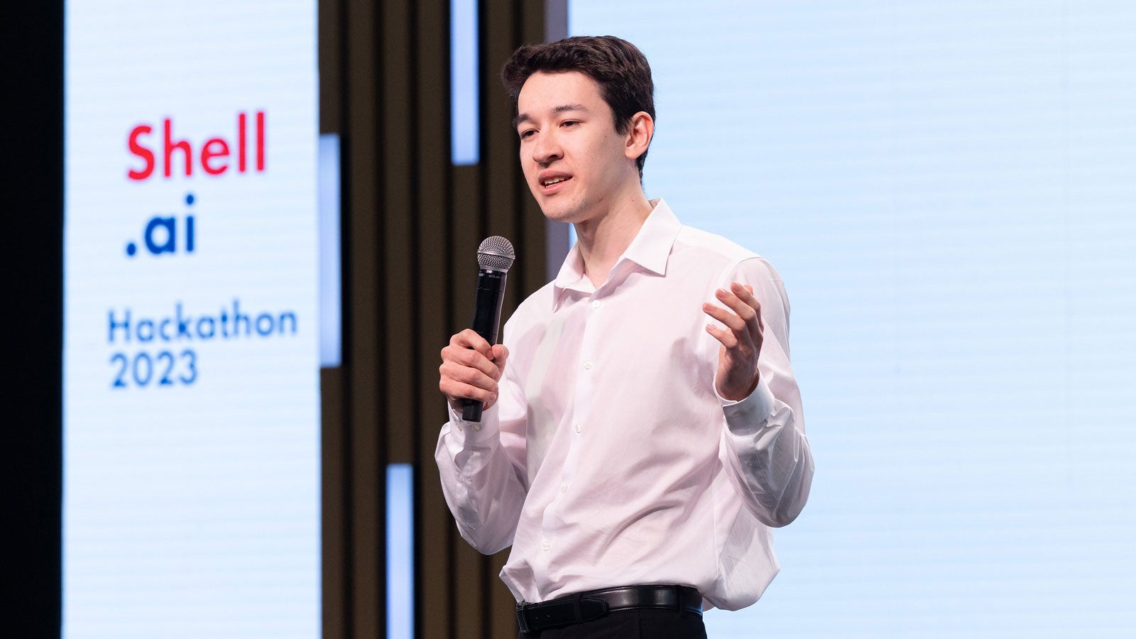 Wei Ping Lam holding microphone and speaking at Hackathon